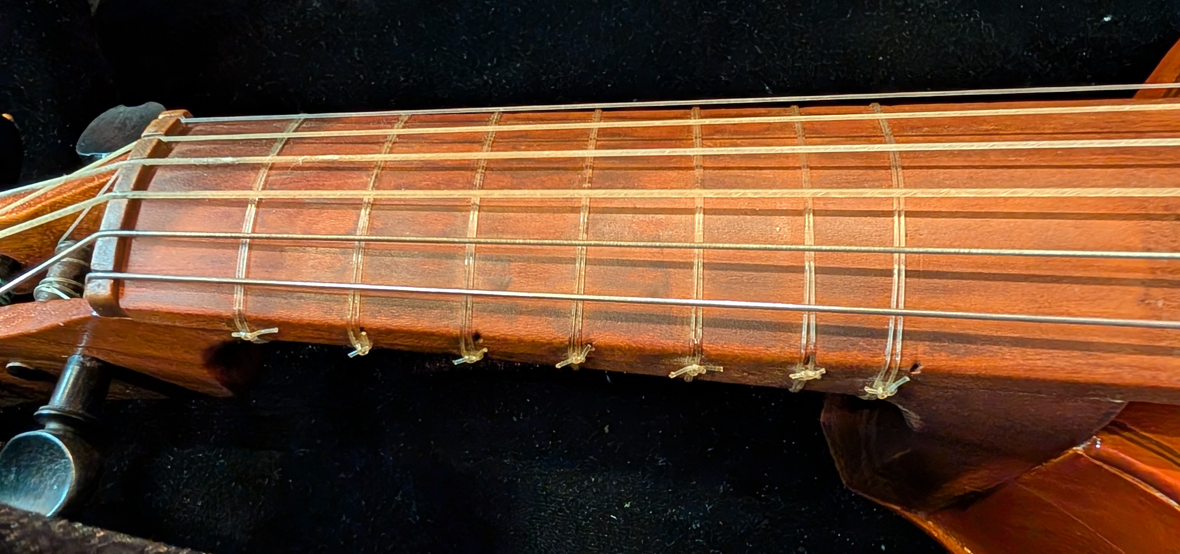 Close up of a treble viol's frets, tied to the fingerboard with nylon.