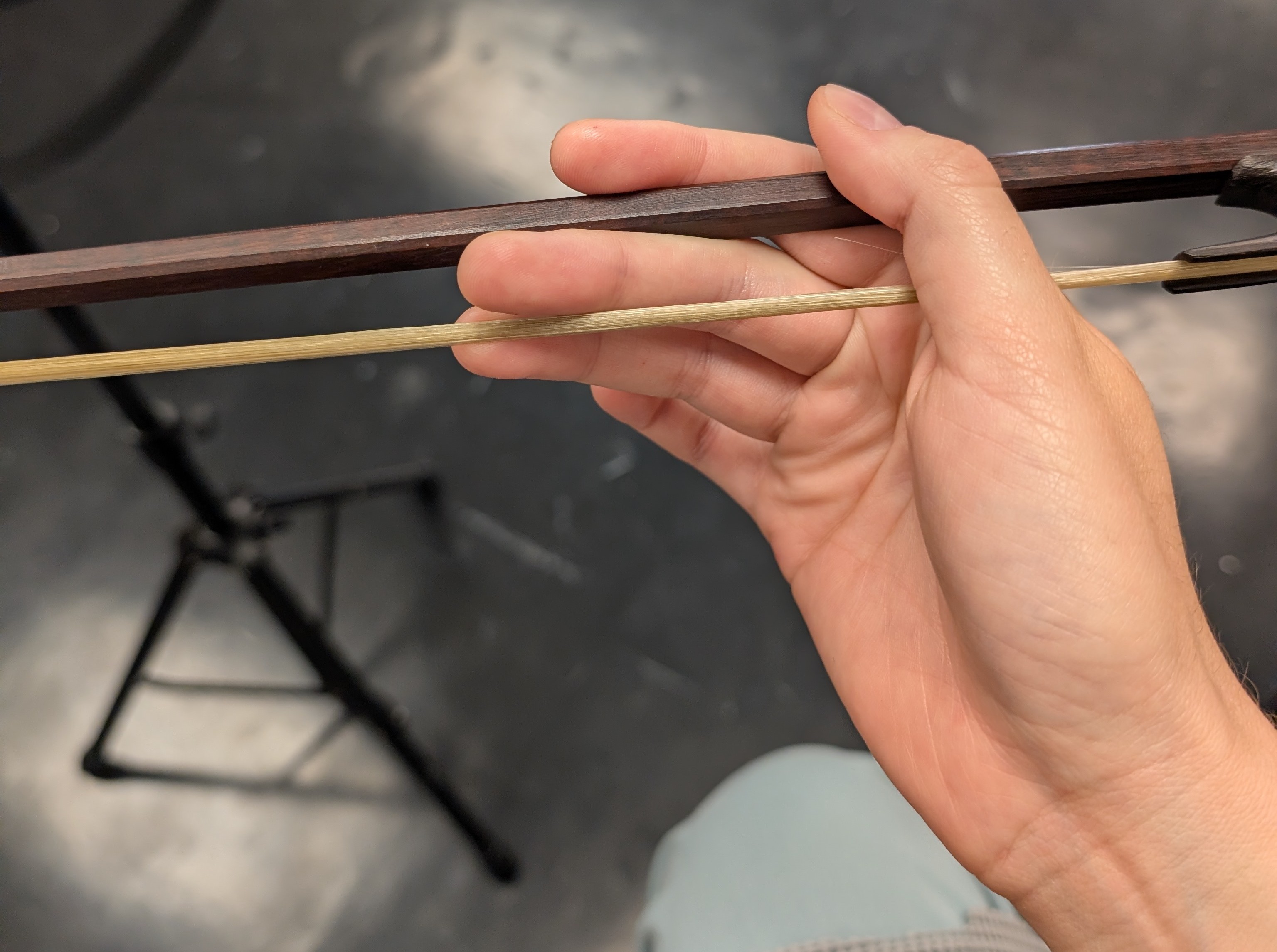A hand awkwardly holding a baroque bow, while touching the hair